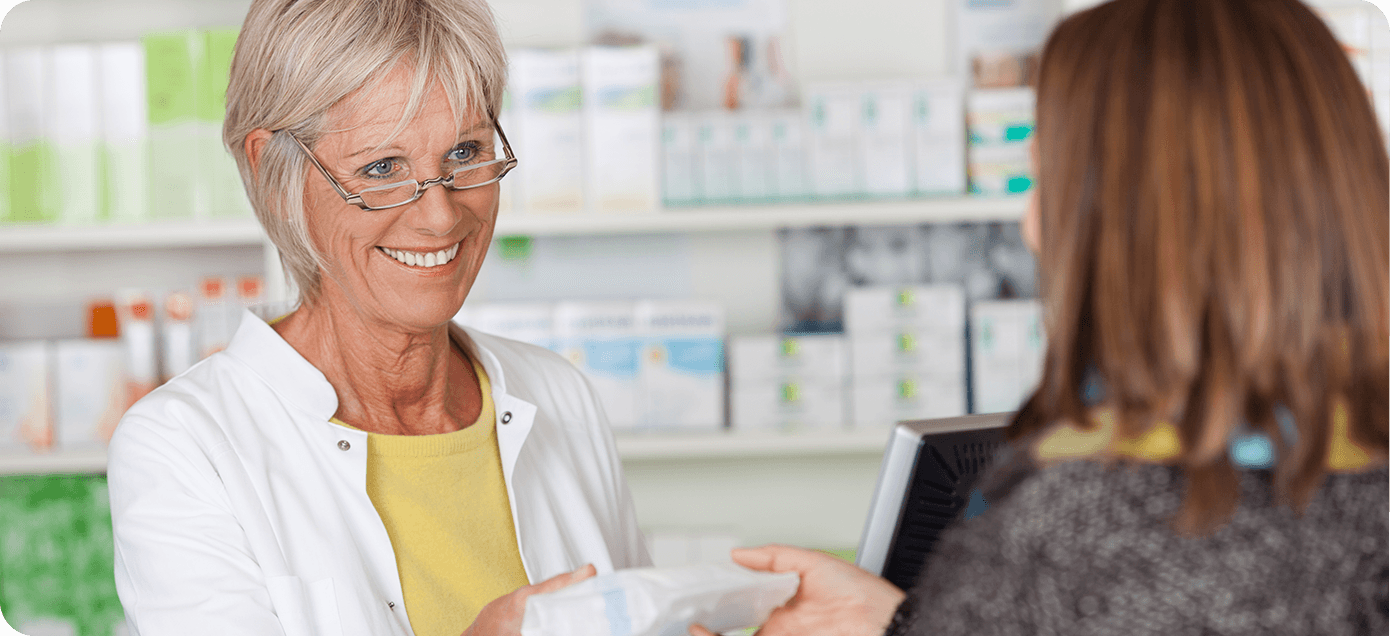 farmacéutica sonriendo y entregando medicamentos a una mujer