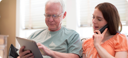 older man showing tablet to younger woman